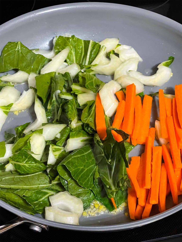 Vegetables for lo mein cooking in a skillet.