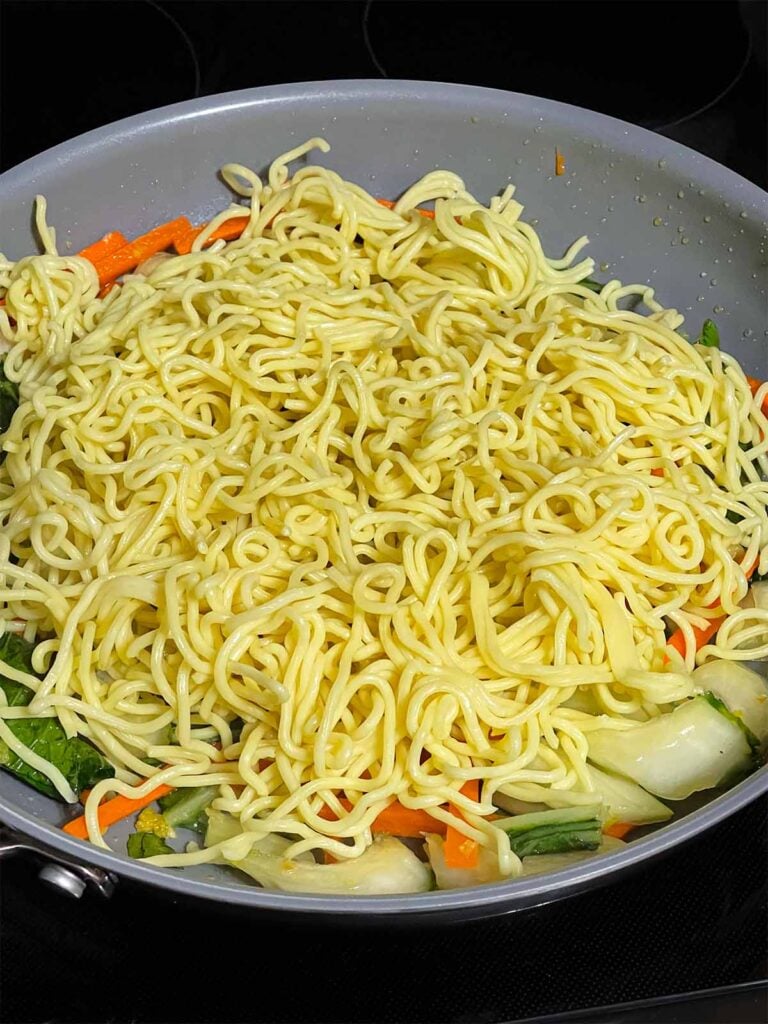Noodles added to a skillet for lo mein.