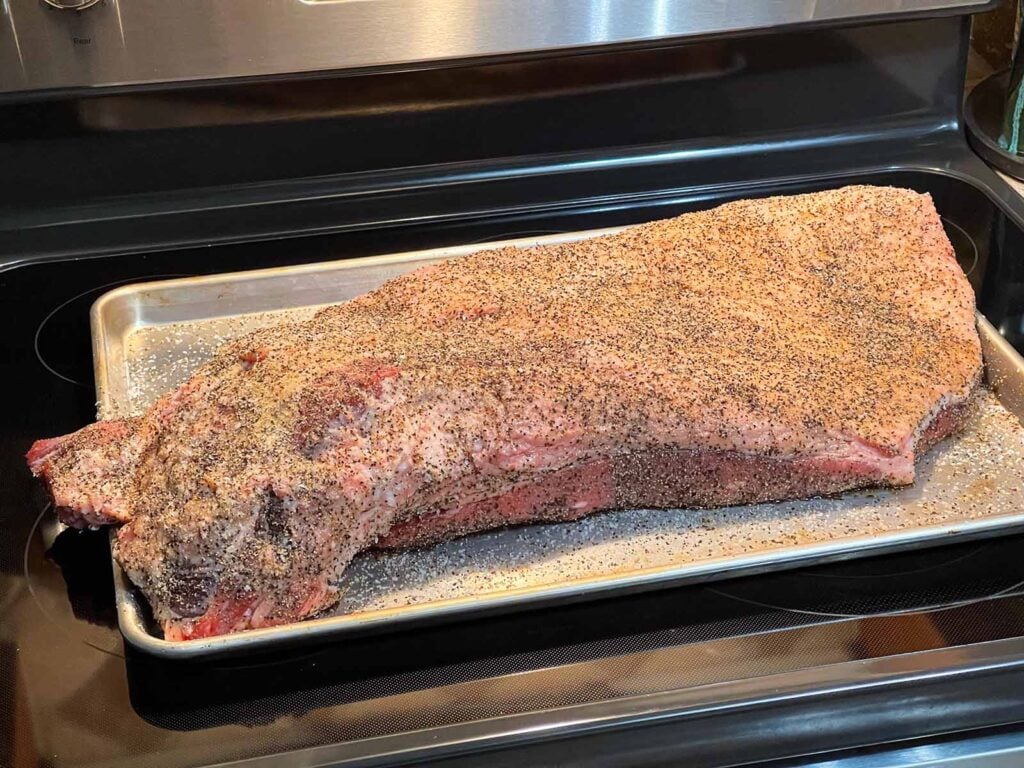 A brisket fully rubbed down with salt and pepper, ready to be smoked.