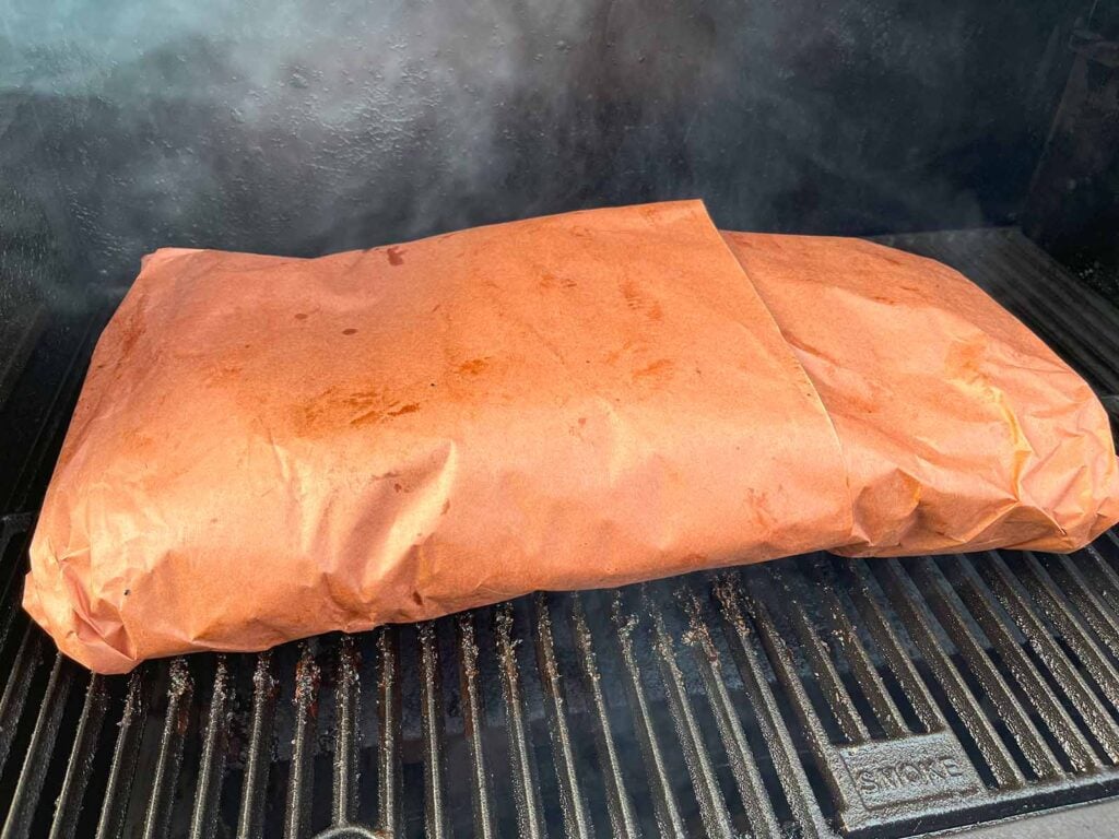 A butcher paper wrapped brisket in a smoker.