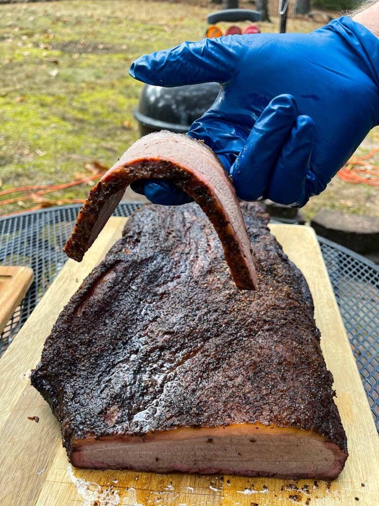 A slice of brisket from the flat being held by a couple of fingers.