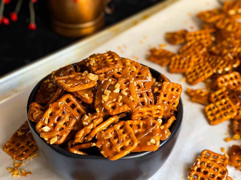 Butter toffee pretzels in a dark bowl on the baking sheet.