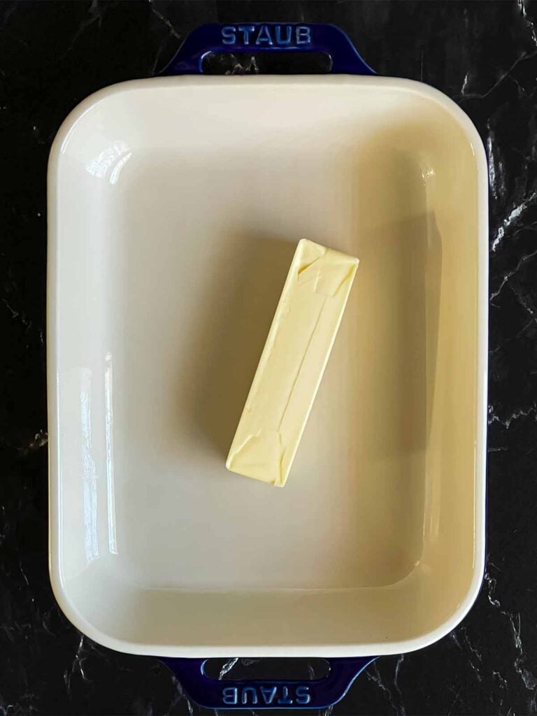 A stick of butter in a casserole dish.