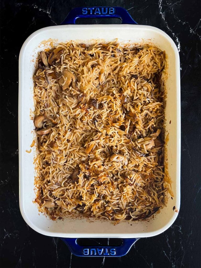 Basmati rice risotto (stick of butter rice) cooked in a casserole dish on a dark surface.