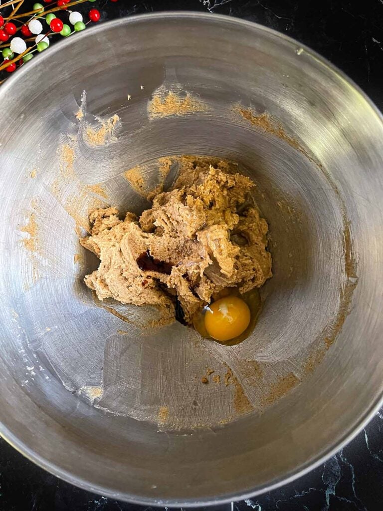 Eggs and vanilla added to the creamed butter and chai sugar mixture in a metal bowl.