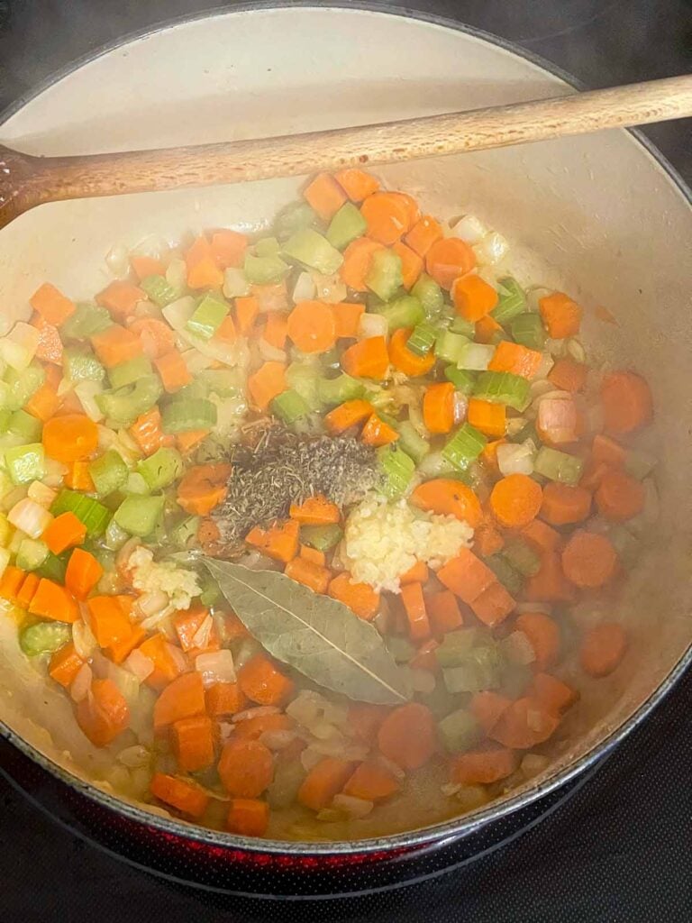 Cooked vegetables with herbs added in a dutch oven.