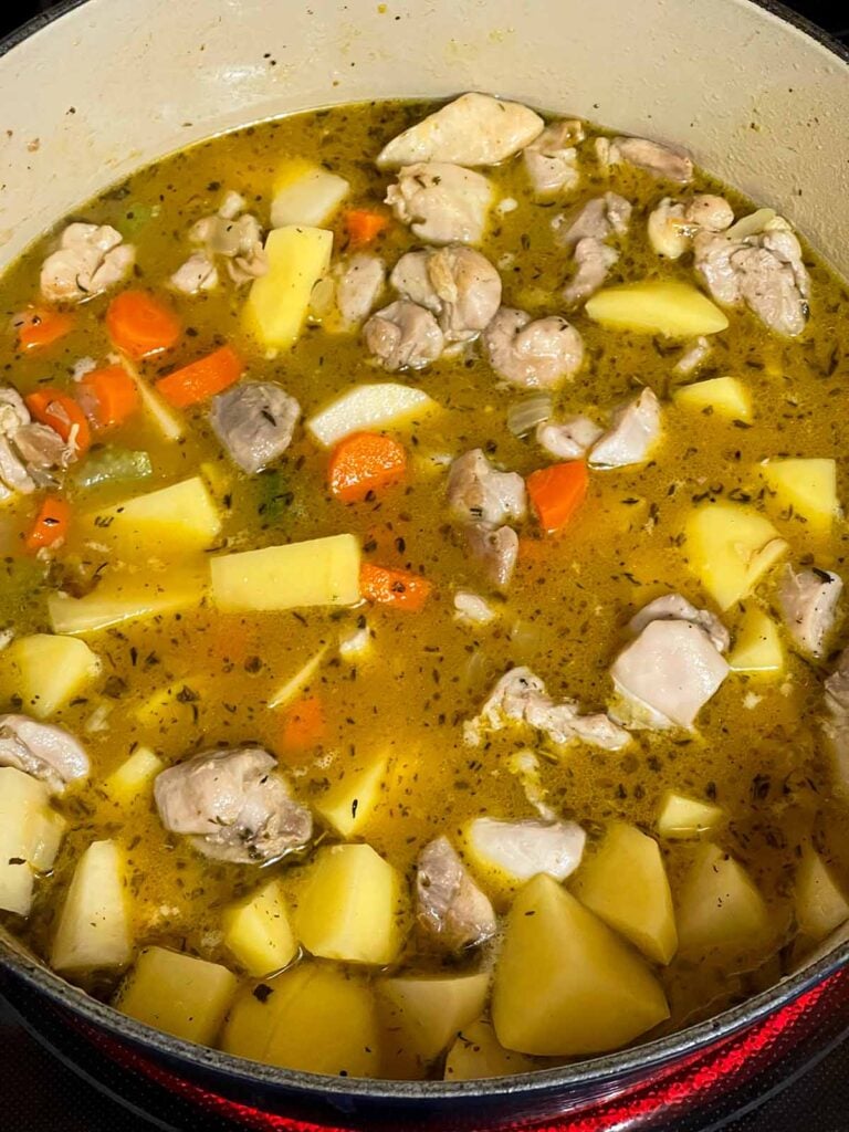 Chicken stew ingredients added to a dutch oven.