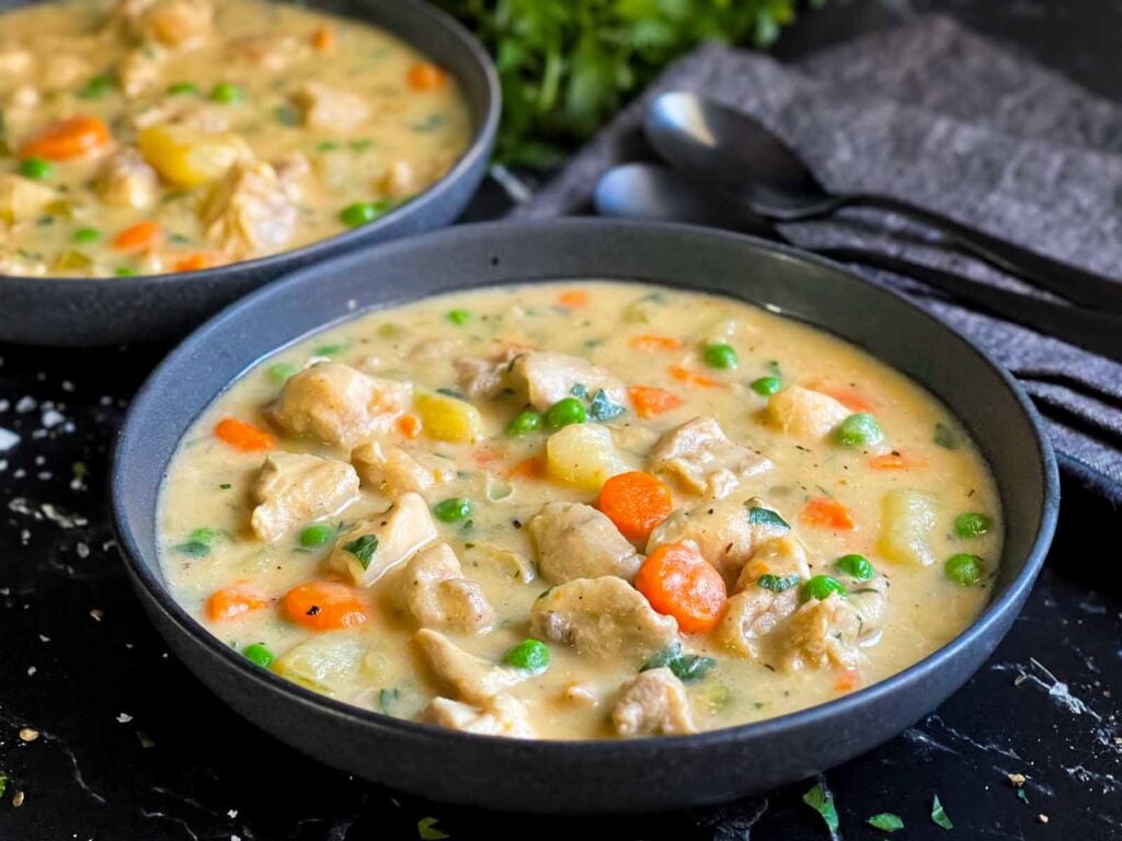 Chicken stew in a dark bowl.