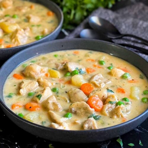 Chicken stew in a dark bowl.