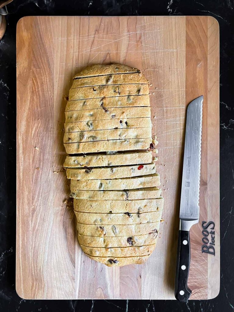 Cranberry pistachio biscotti sliced into pieces on a wooden board.