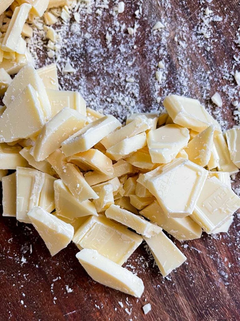 Chopped baking white chocolate bars on a wooden board.