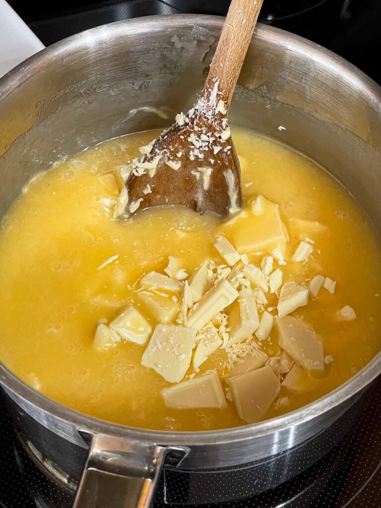 The chopped chocolate added to the boiled eggnog fudge ingredients in a saucepan.