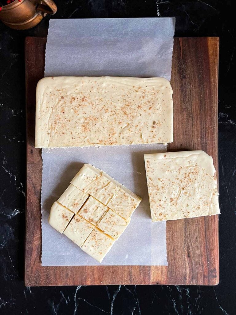 Eggnog fudge cut into serving pieces on a wooden board.