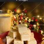 Eggnog fudge stacked on a dark plate with a glass of eggnog.