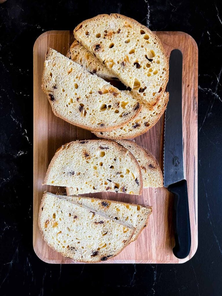 Panettone sliced into half moon slices on a wooden board.