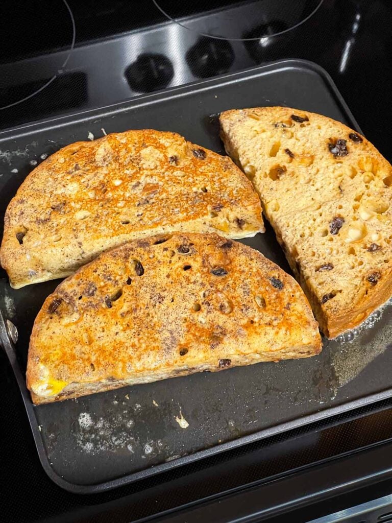 Slices of panettone french toast cooking on a buttered griddle.