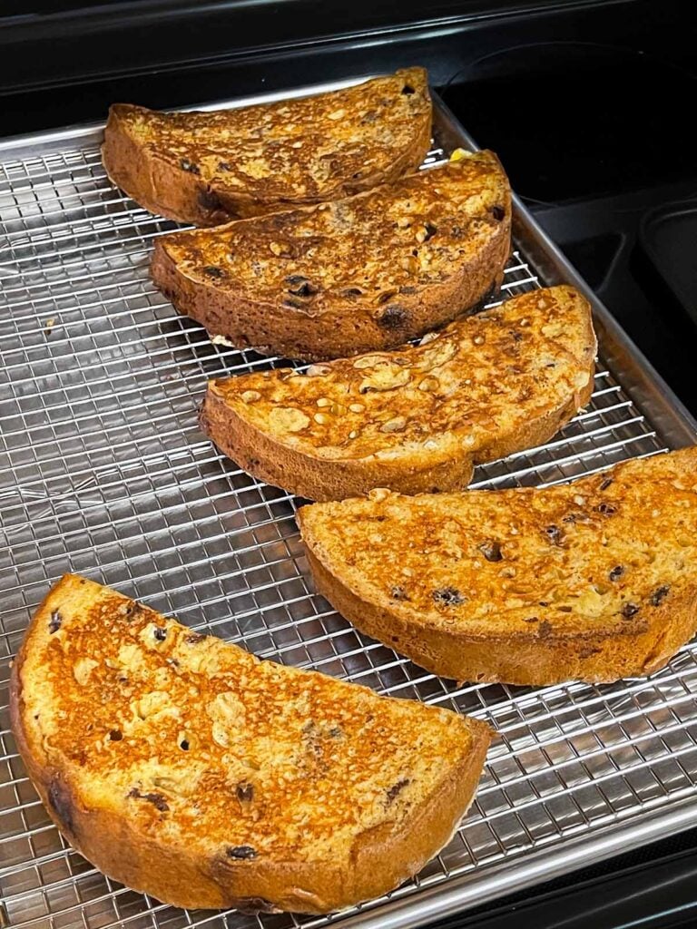 Cooked panettone french toast on a wire rack lined baking sheet.