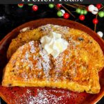 Slices of panettone French toast garnished with powdered sugar, whipped cream, and maple syrup on a red plate.