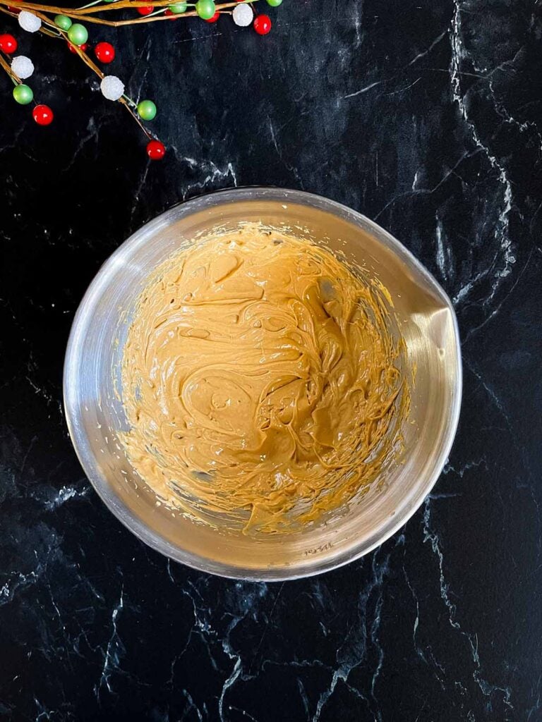 Peanut butter and softened butter mixed together in a metal mixing bowl.