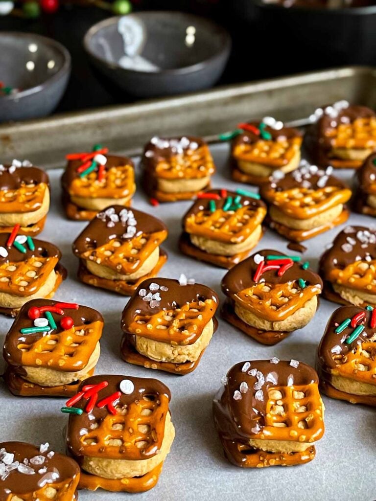 Chocolate covered peanut butter pretzel bites on a parchment paper lined baking sheet.