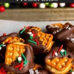 Chocolate covered peanut butter pretzel bites stacked on a parchment paper lined baking sheet.