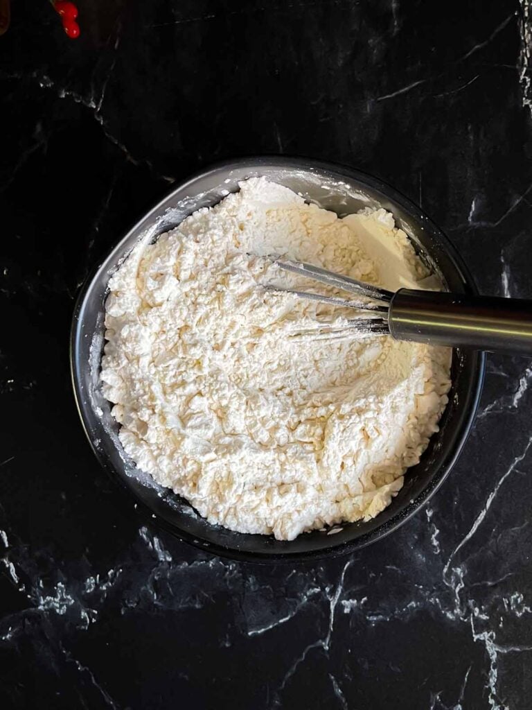 All-purpose flour, cornstarch, and kosher salt whisked together in a dark bowl.