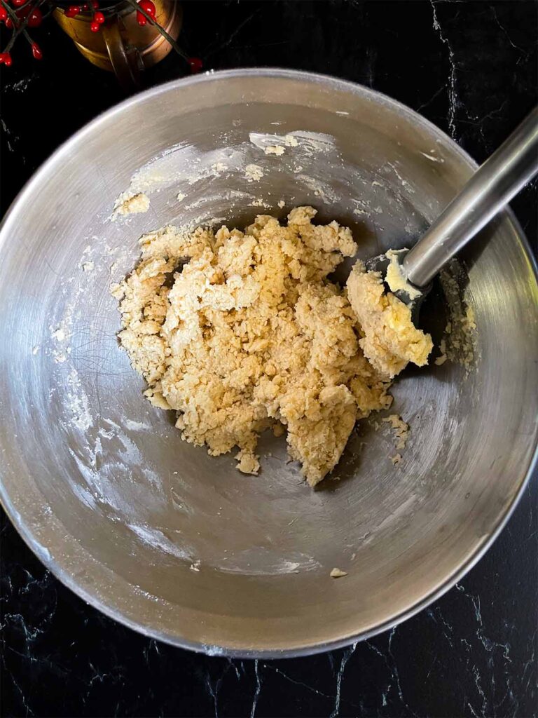 Flour mixture added to the whipped butter and sugar in a metal mixing bowl.