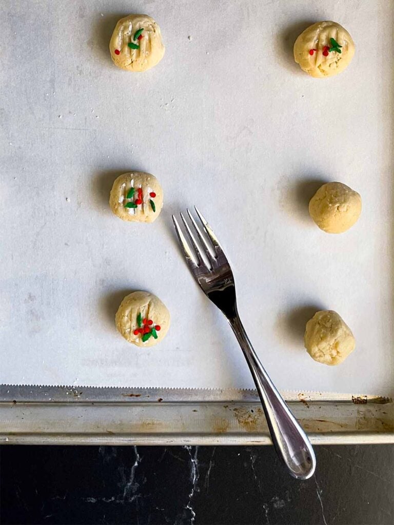 Whipped shortbread cookie dough balls formed and placed on a parchment paper lined baking sheet.