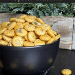 Dill oyster crackers in a dark bowl on a dark surface.