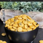 Dill oyster crackers in a dark bowl on a dark surface.