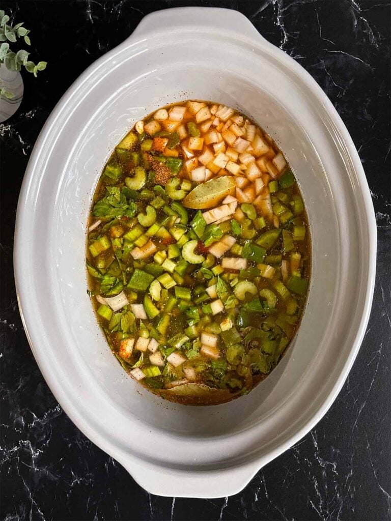 Chicken stock added to the red beans and rice ingredients in the crock of a slow cooker.