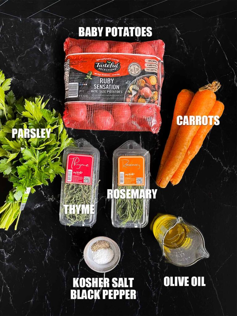 Ingredients for roasted potatoes and carrots on a dark surface.