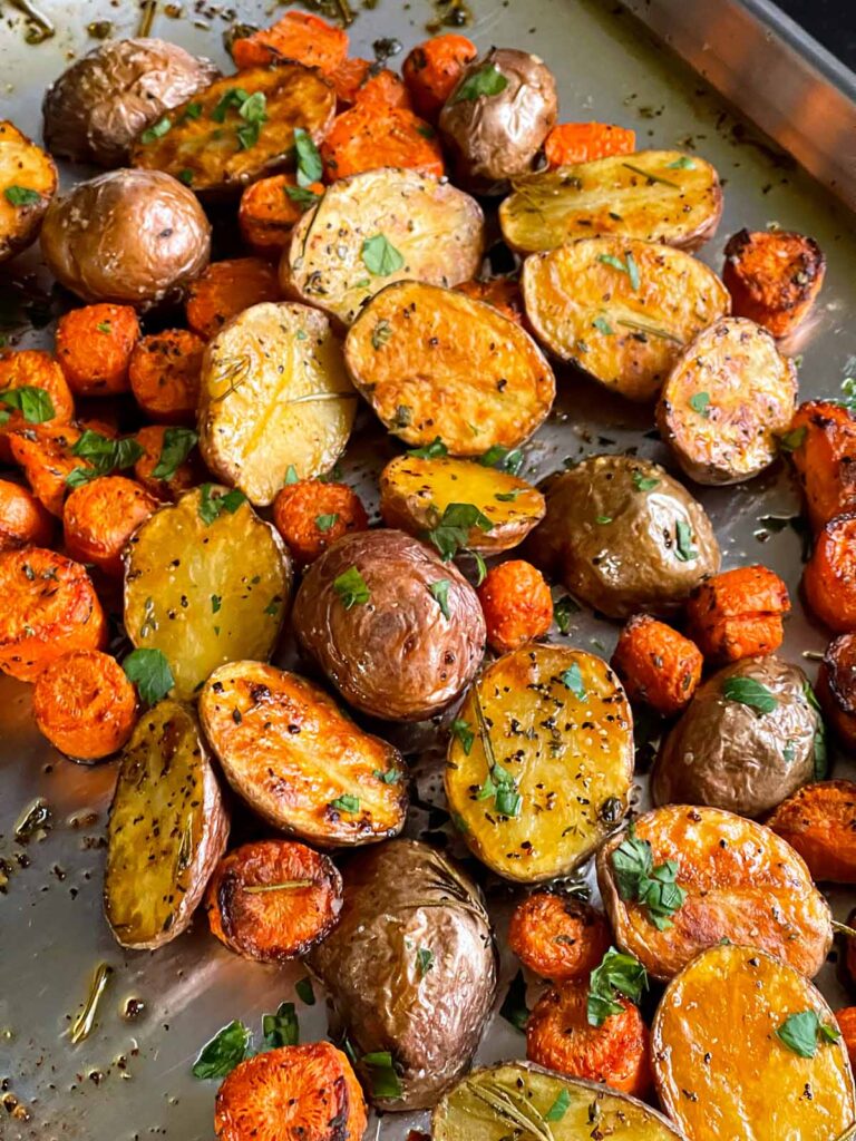 Roasted potatoes and carrots on a baking sheet.