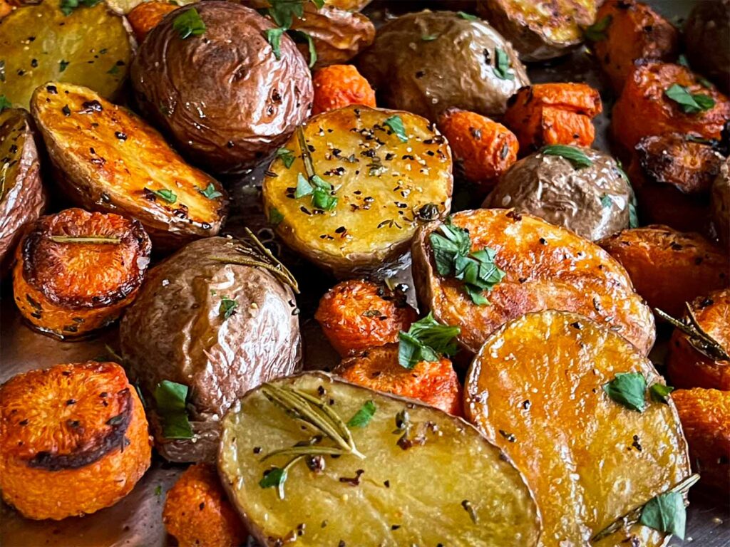 Roasted potatoes and carrots on a baking sheet.