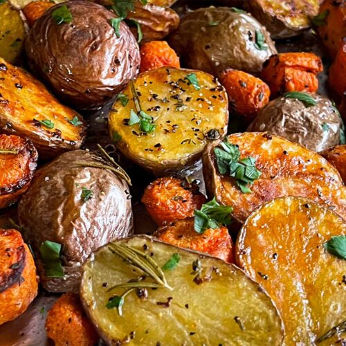 Roasted potatoes and carrots on a baking sheet.