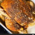 Slow cooker roasted chicken in a serving dish on a dark surface.