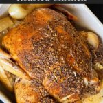 Slow cooker roasted chicken in a serving dish on a dark surface.