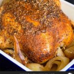 Slow cooker roasted chicken in a serving dish on a dark surface.