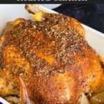 Slow cooker roasted chicken in a serving dish on a dark surface.