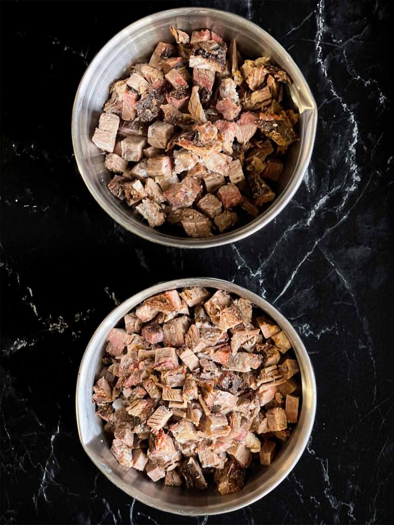 Smoked brisket cubed in a couple stainless steel bowls.