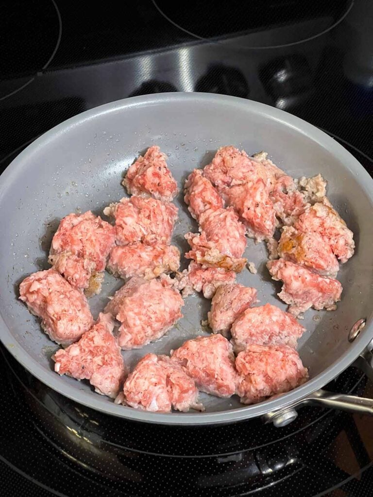 Breakfast sausage cooking in a small skillet.