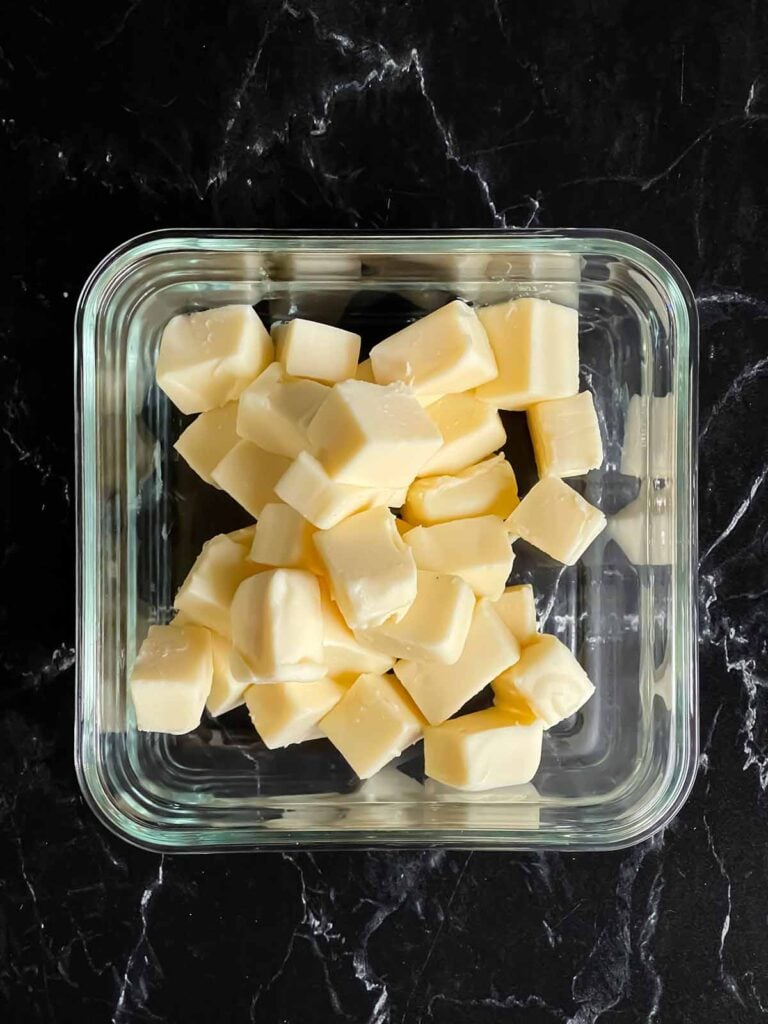 Velveeta cheese cubed in a glass container.