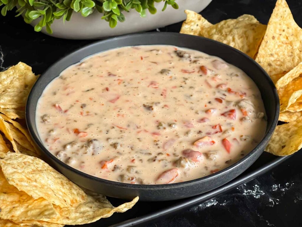 Velveeta cheese dip in a dark bowl with tortilla chips.