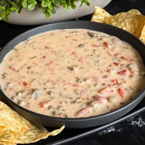 Velveeta cheese dip in a dark bowl with tortilla chips.