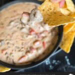 Velveeta cheese dip in a dark bowl with tortilla chips on the side.