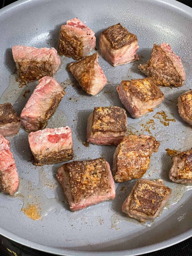 Seared beef tips in a skillet.