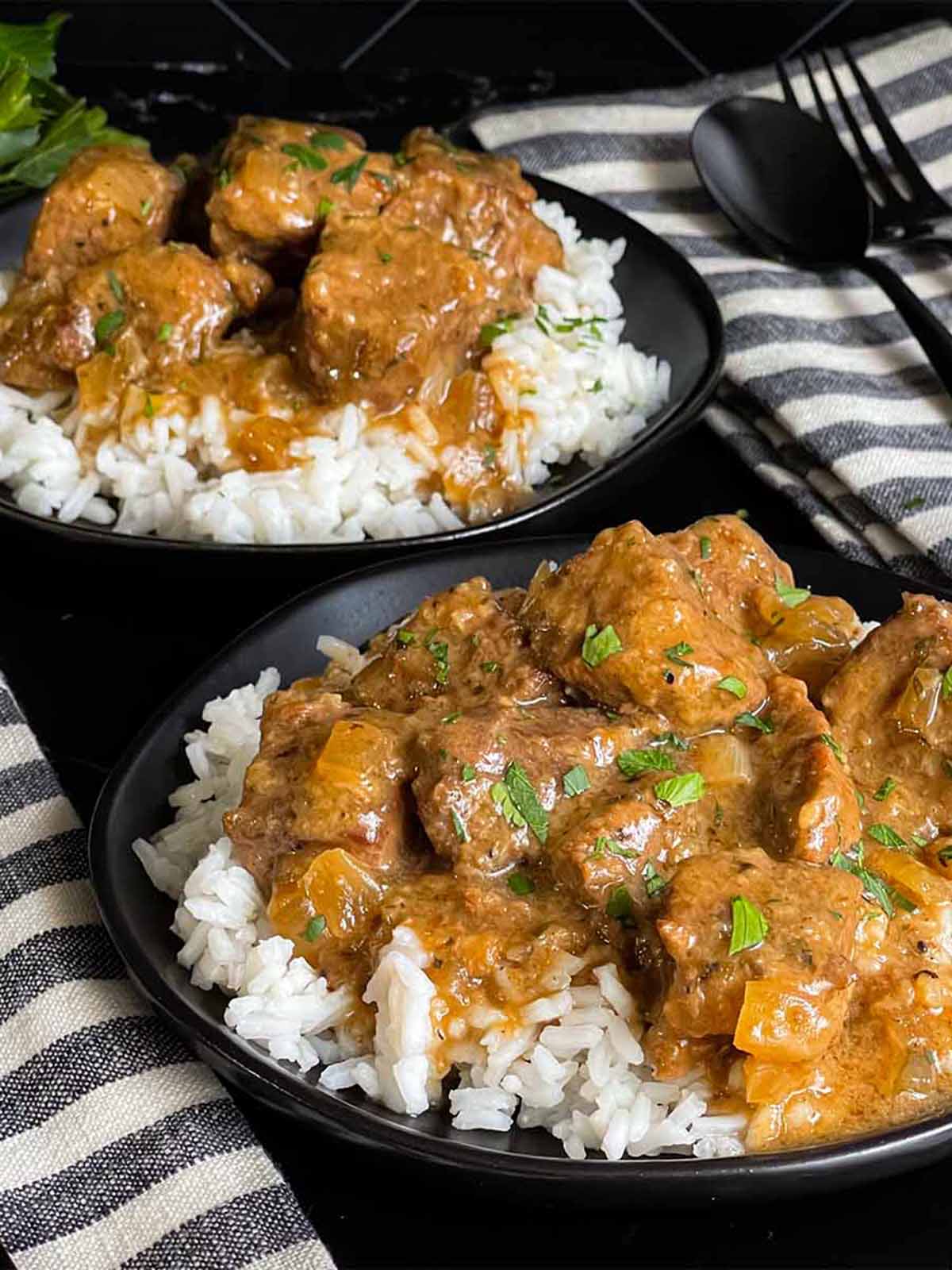 Slow cooker beef tips and gravy over white rice in a bowl.