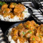 Slow cooker beef tips and gravy over cooked rice on a dark plate on a dark surface.