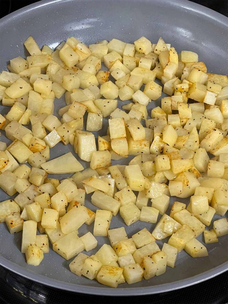 Diced, seasoned potatoes in a skillet.