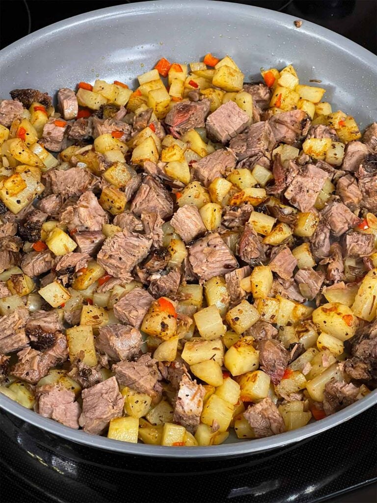 Brisket hash cooking in a skillet.